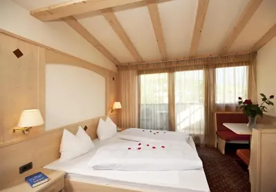 a bedroom with a large white bed with red roses on it at Pension Golser in Cermes