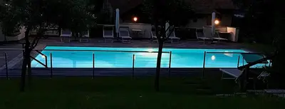 a swimming pool at night with chairs around it at Pension Golser in Cermes