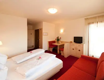 a hotel room with two beds and a table at Pension Golser in Cermes