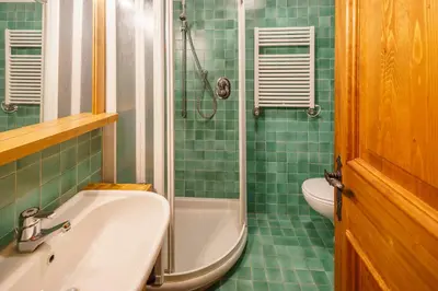 a green tiled bathroom with a sink and a shower at Villa Franchetti - Stayincortina in Cortina dʼAmpezzo