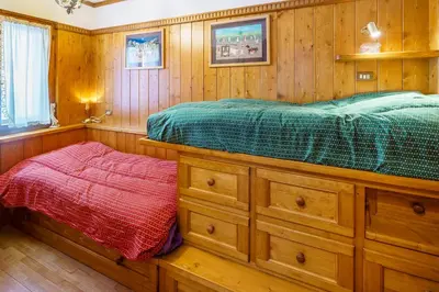 a bedroom with a large bed and a red bed sidx sidx sidx at Villa Franchetti - Stayincortina in Cortina dʼAmpezzo