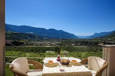 a table with food and drinks on a balcony with mountains at Panorama Residence Öhlerhof in Lagundo
