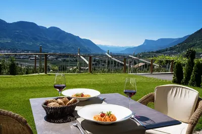 a table with two plates of food and wine glasses at Panorama Residence Öhlerhof in Lagundo