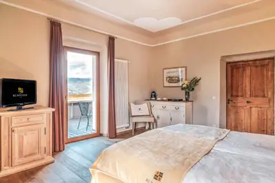 a bedroom with a bed and a desk and a window at Hotel Ansitz Rungghof in Appiano sulla Strada del Vino