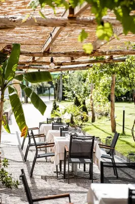 a row of tables and chairs under a pergola at Hotel Ansitz Rungghof in Appiano sulla Strada del Vino