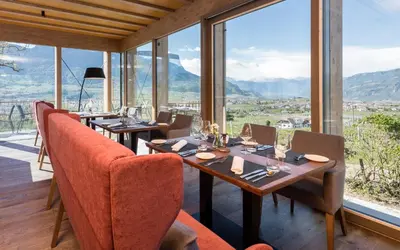a restaurant with tables and chairs and large windows at Hotel Ansitz Rungghof in Appiano sulla Strada del Vino