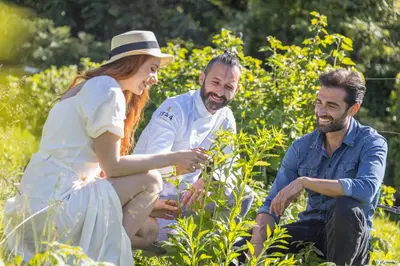a group of three people sitting in a garden at Hotel Ansitz Rungghof in Appiano sulla Strada del Vino