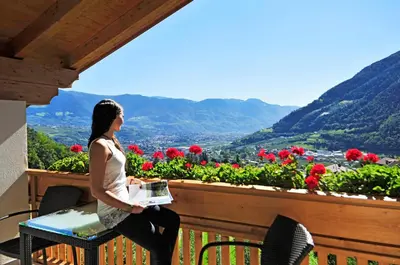 a woman sitting on a table on a balcony with flowers at Seppmair in Lagundo