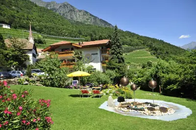 a garden with a table and chairs and a building at Seppmair in Lagundo