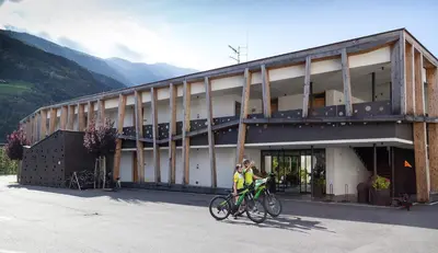 two people on bikes in front of a building at Residence & Sportlodges Claudia in Plaus