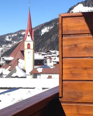 a view of a church in the snow from a building at Appartamenti Chedul in Selva di Val Gardena