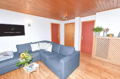 a living room with a blue couch and wooden floors at Appartamenti Chedul in Selva di Val Gardena