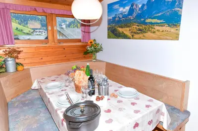 a table with a white table cloth and wine bottles at Appartamenti Chedul in Selva di Val Gardena