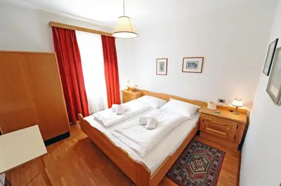 a bedroom with a bed with white sheets and a window at Apartments Valverda in Ortisei