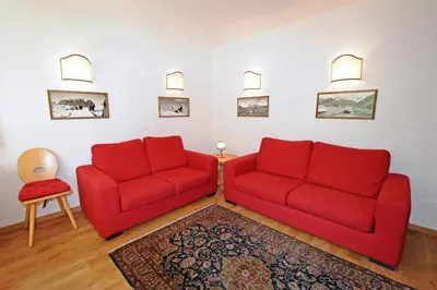 a living room with two red chairs and a rug at Apartments Valverda in Ortisei