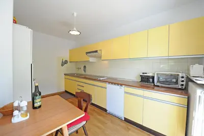 a kitchen with yellow cabinets and a wooden table at Apartments Valverda in Ortisei
