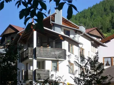 a white building with balconies and a mountain at Apartments Haus Martin in Nova Levante
