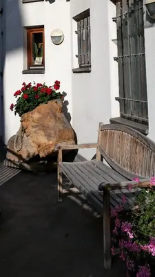 a wooden bench next to a tree stump with flowers at Apartments Haus Martin in Nova Levante