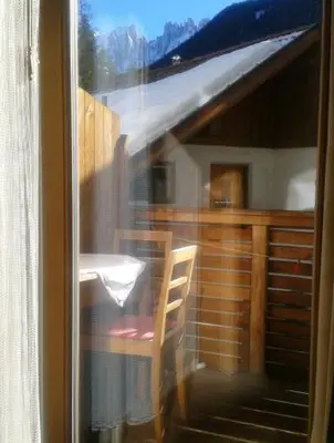 a view of a table and a chair through a window at Apartments Haus Martin in Nova Levante
