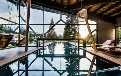 a pool in a house with a view of the mountains at Hotel Alpenrose in Carezza al Lago