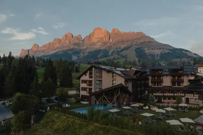 a resort with a mountain in the background at Hotel Alpenrose in Carezza al Lago