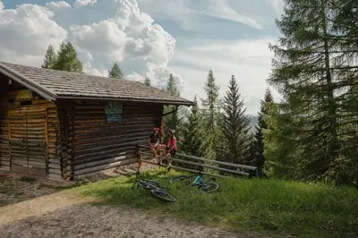 two people sitting on a fence next to a cabin at Hotel Alpenrose in Carezza al Lago