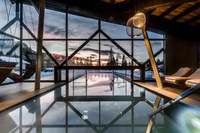 a house with a swimming pool with a view of the mountains at Hotel Alpenrose in Carezza al Lago