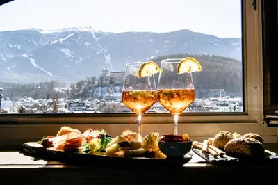 a table with two glasses of wine and a plate of food at Hotel ANDER in Brunico