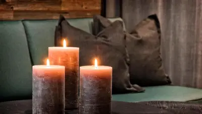 two candles sitting on a table in front of a couch at Hotel ANDER in Brunico