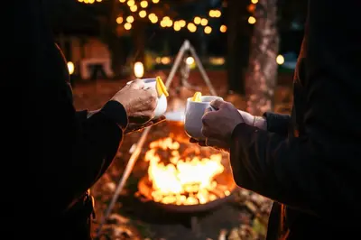 two people holding cups in front of a fire at Hotel ANDER in Brunico
