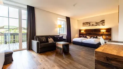 a hotel room with a bed and a couch at Hotel ANDER in Brunico