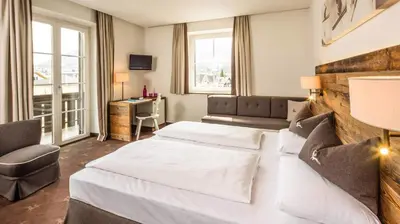 a hotel room with two beds and a desk at Hotel ANDER in Brunico