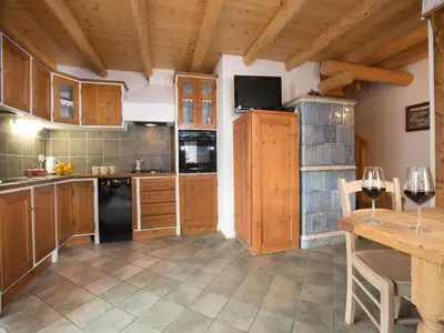 a kitchen with wooden cabinets and a black refrigerator at Typical Cottage in Bellamonte Italy with bubble bath in Bellamonte