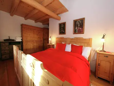 a bedroom with a large bed with red pillows at Typical Cottage in Bellamonte Italy with bubble bath in Bellamonte