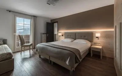 a bedroom with a large bed and a window at Hotel Villa Argentina in Cortina dʼAmpezzo