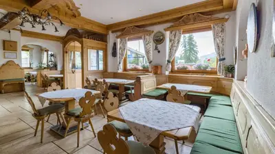 a dining room with tables and chairs and windows at Hotel Villa Argentina in Cortina dʼAmpezzo