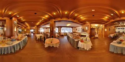 a dining room with tables and chairs in a building at Hotel Villa Argentina in Cortina dʼAmpezzo
