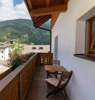 a balcony with a table and chairs and a view at Hölzlhof Apartments in Rasun di Sopra