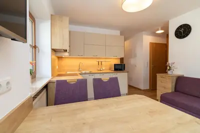 a kitchen with a table and purple chairs in a room at Hölzlhof Apartments in Rasun di Sopra