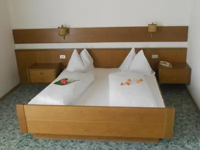 a large bed with white sheets and flowers on it at Garni Unterspeiser in Terlano