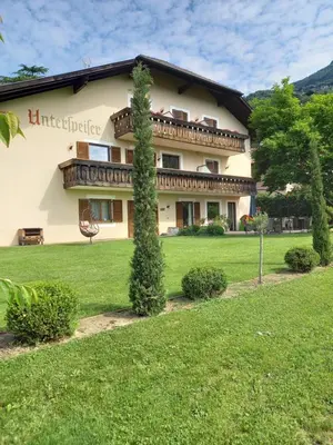 a large building with a green lawn in front of it at Garni Unterspeiser in Terlano