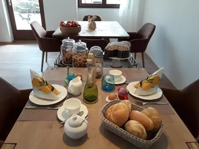 a table with a breakfast of croissants bread and tea at Garni Unterspeiser in Terlano