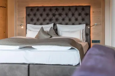 a bedroom with a large bed with a large headboard at Hotel Madonna in Castelrotto