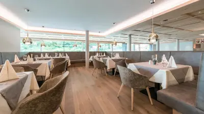 a restaurant with white tables and chairs and windows at Hotel Madonna in Castelrotto