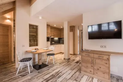 a kitchen with a table and chairs and a television on the wall at Osti Nicl in San Martino in Badia