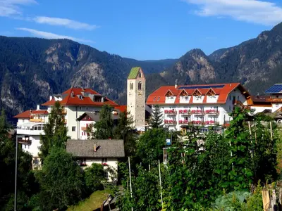 a group of buildings with a clock tower and mountains at Gasthaus zum Weissen Kreuz in Lazfons