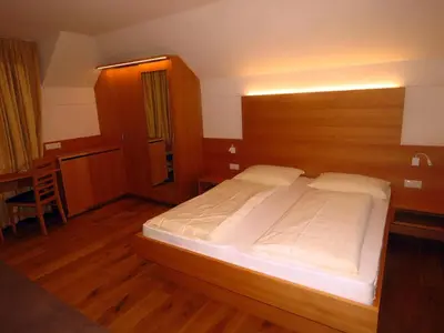 a bedroom with a large bed with a wooden headboard at Gasthaus zum Weissen Kreuz in Lazfons