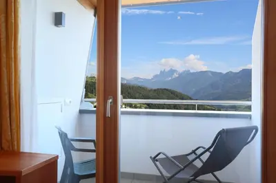a chair on a balcony with a view of mountains at Gasthaus zum Weissen Kreuz in Lazfons