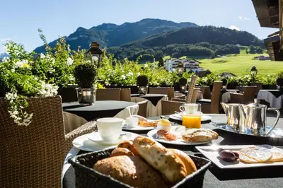 a table with a breakfast of bread and orange juice at Hotel MAYR in Castelrotto