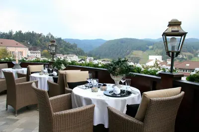 a restaurant with tables and chairs with mountains in the background at Hotel MAYR in Castelrotto